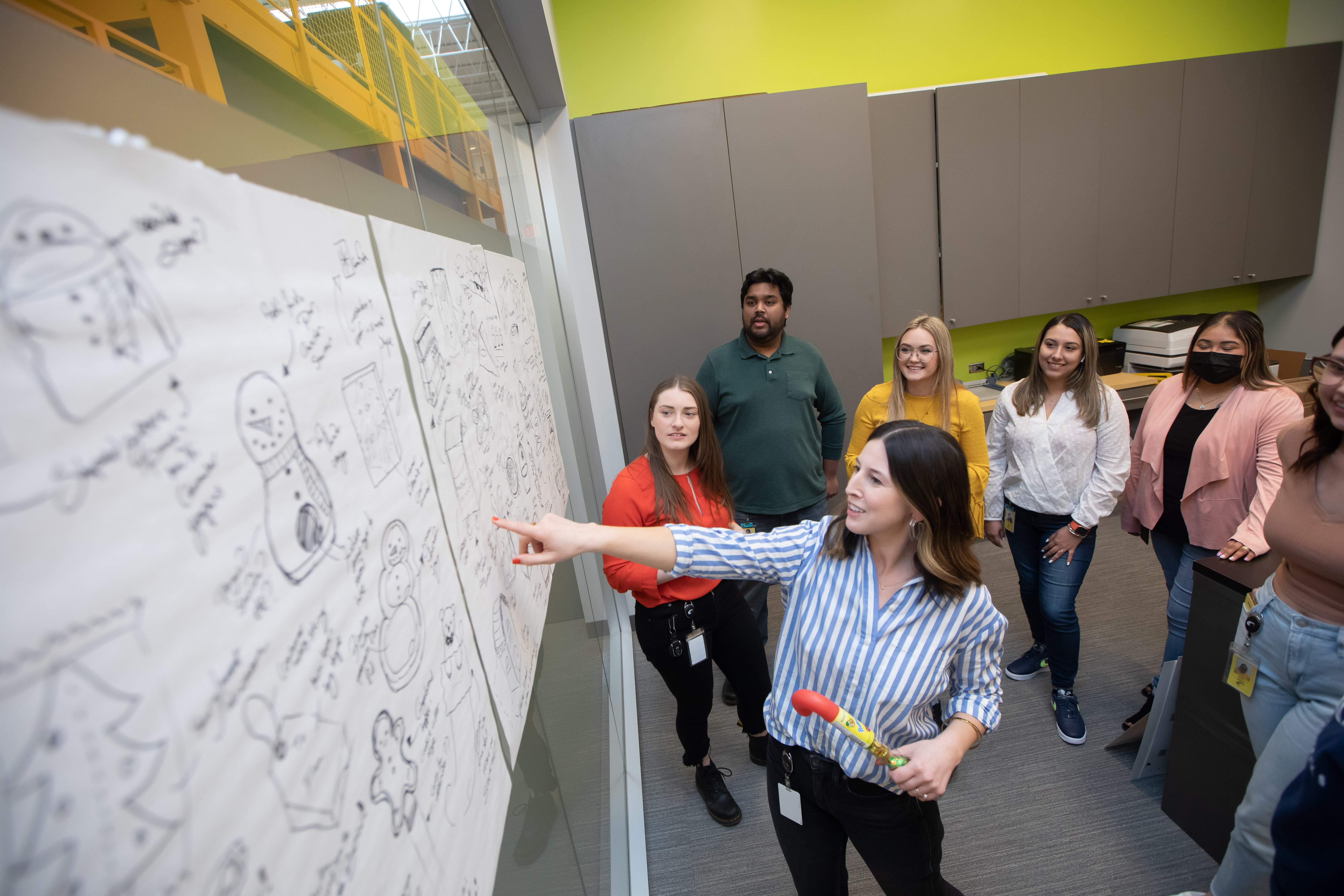 Industrial Designers standing in front of posters with drawings of packaging